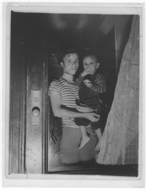 Bernice Lythcott and her one-year-old son Leonard look out a window through which hoodlums threw stones, 1943