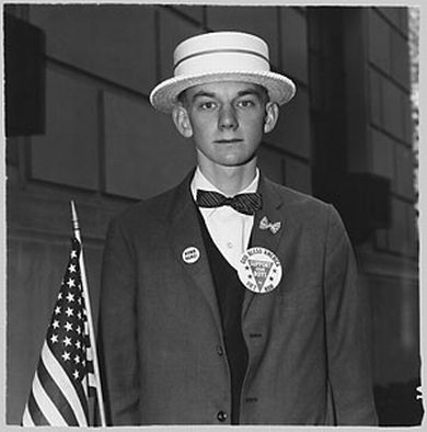 Diane Arbus - A boy with a straw hat and flag waiting to march in a pro-war parade, 1967