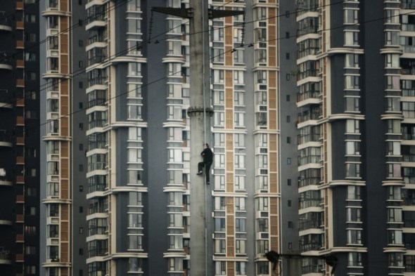 Shaofeng Xu - Un hombre escala por una torre de electricidad de alto voltaje en Ghengdu, Sichuán, China. Quería llamar la atención por el hecho de que no había recibido compensación alguna del gobierno por la demolición de su casa.